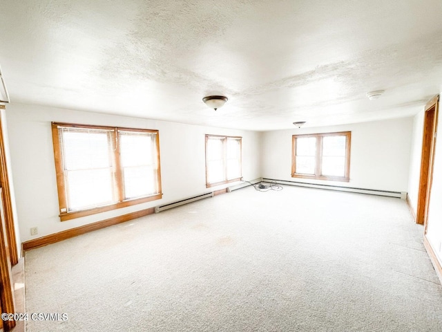 empty room with light carpet, a textured ceiling, and a baseboard heating unit