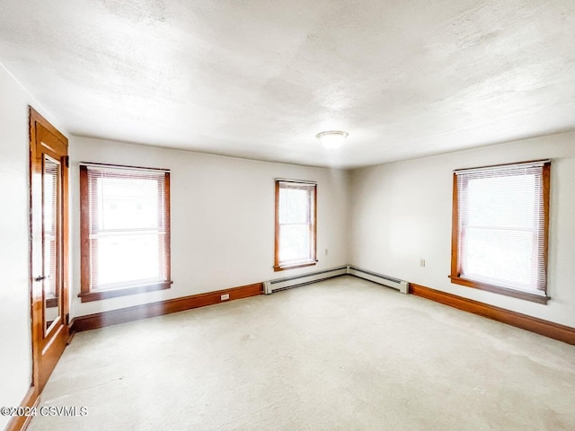 carpeted empty room featuring a textured ceiling, a baseboard radiator, and plenty of natural light