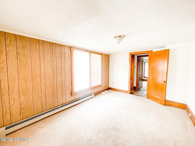 carpeted spare room with wood walls and baseboard heating