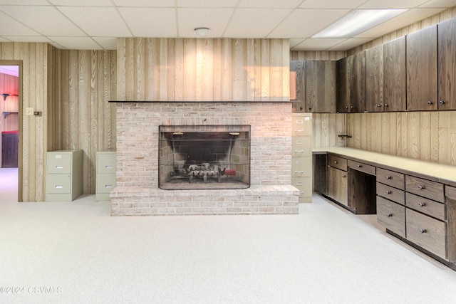 unfurnished living room with a paneled ceiling, a fireplace, built in desk, and light carpet