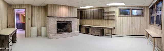 living room featuring baseboard heating, a drop ceiling, and wooden walls