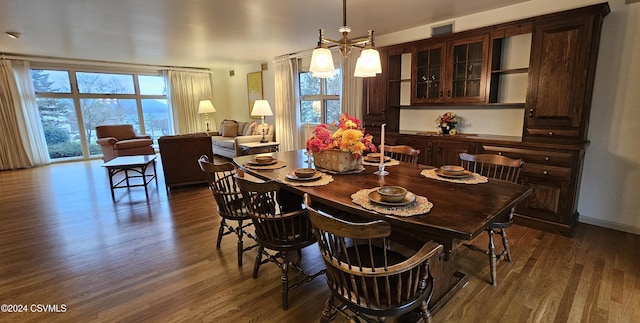 dining space with dark wood-type flooring and a notable chandelier