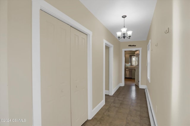 corridor with a baseboard heating unit and a notable chandelier