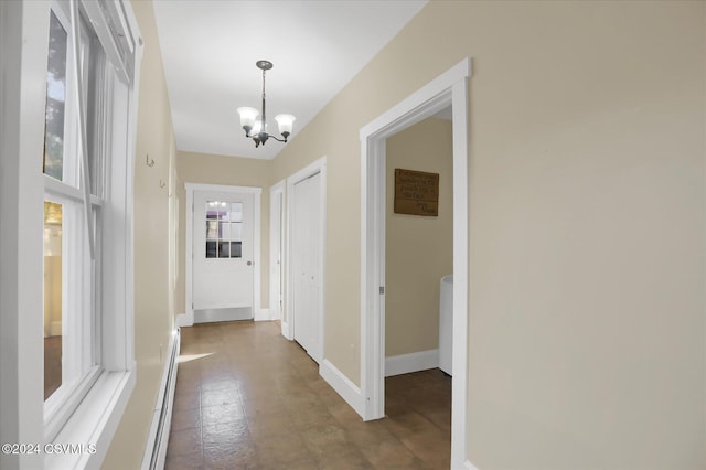 corridor featuring a baseboard heating unit and a notable chandelier