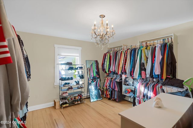 spacious closet with light wood-type flooring and an inviting chandelier