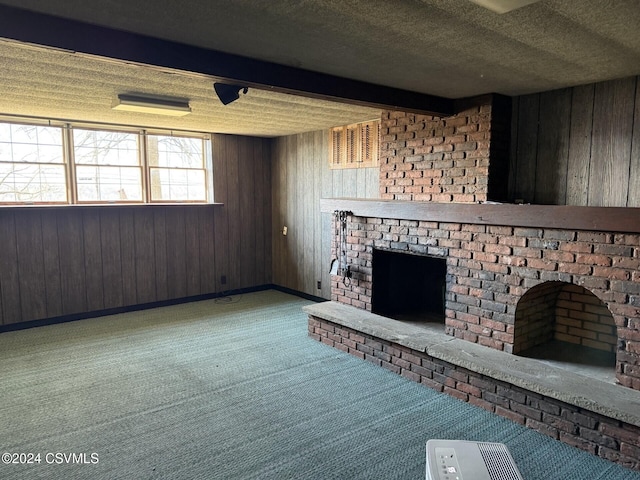 unfurnished living room featuring beamed ceiling, carpet, and a textured ceiling