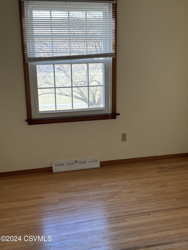 spare room featuring baseboard heating and light hardwood / wood-style floors