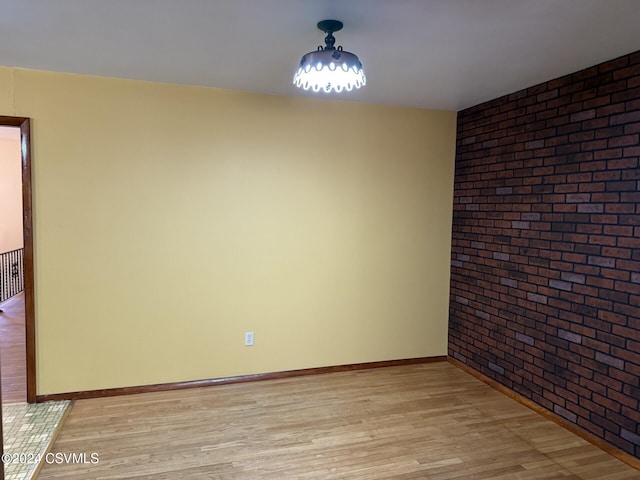 empty room featuring light hardwood / wood-style floors and brick wall