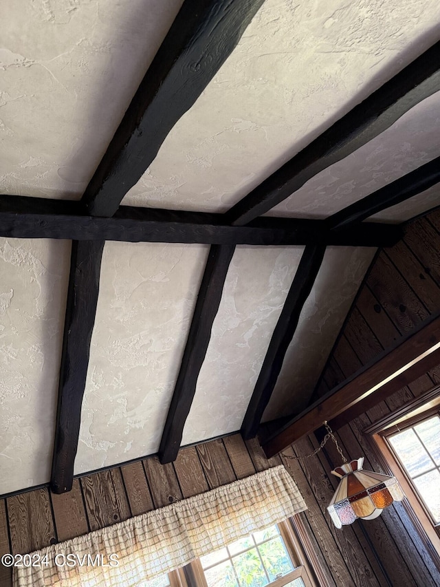 room details with beam ceiling, wooden walls, and a textured ceiling