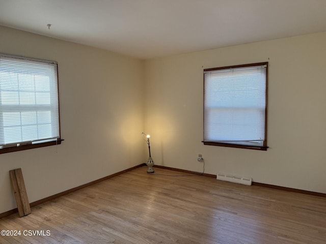 empty room with baseboard heating and light hardwood / wood-style flooring