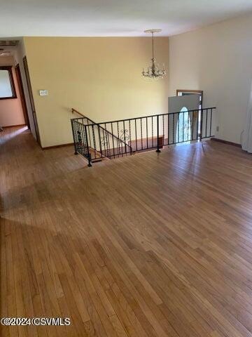 spare room with dark hardwood / wood-style floors and an inviting chandelier