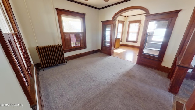 524 Front St, New Berlin, PA 17855 - empty room featuring radiator heating unit, carpet, ornamental molding, ceiling fan, and arched walkways