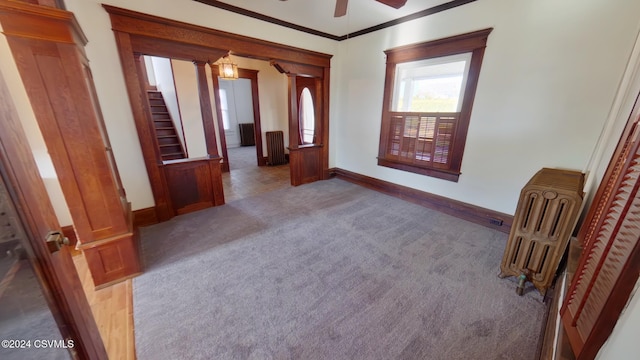 524 Front St, New Berlin, PA 17855 - carpeted empty room with a ceiling fan, ornamental molding, radiator, stairs, and decorative columns