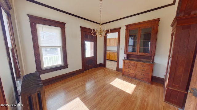 unfurnished dining area with radiator heating unit, light wood-type flooring, crown molding, and a notable chandelier