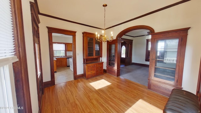 unfurnished dining area with plenty of natural light, light hardwood / wood-style floors, ornamental molding, and a chandelier