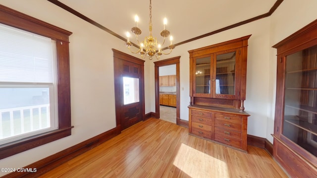 entrance foyer with light hardwood / wood-style floors, crown molding, and an inviting chandelier