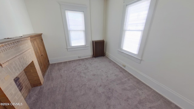 empty room with light carpet, radiator, and a fireplace