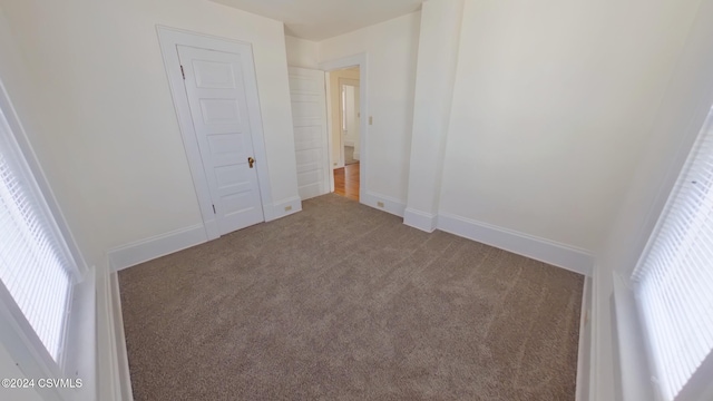 unfurnished bedroom with carpet flooring, a closet, and multiple windows