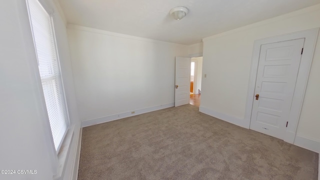 unfurnished bedroom featuring light carpet, multiple windows, and crown molding