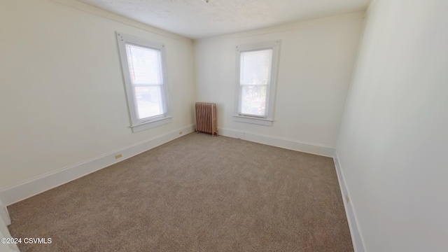 unfurnished room with light colored carpet and radiator