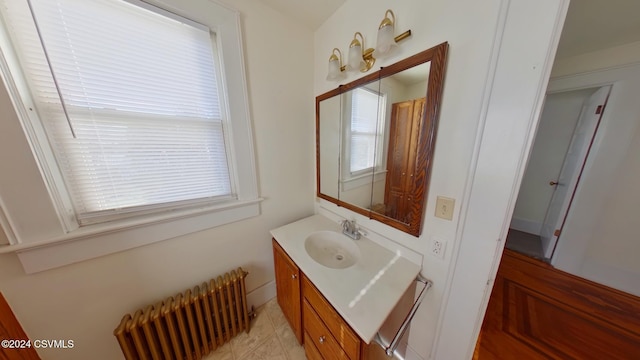 bathroom with radiator heating unit, vanity, and a healthy amount of sunlight