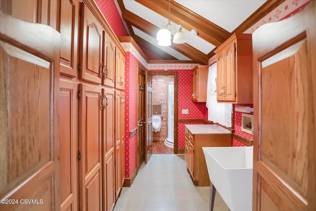 kitchen with lofted ceiling, sink, hanging light fixtures, ornamental molding, and a chandelier