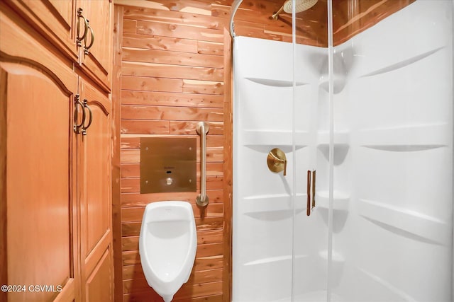 bathroom with wood walls and an enclosed shower