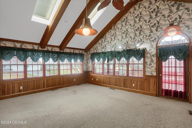 carpeted spare room with high vaulted ceiling, wooden walls, and a skylight