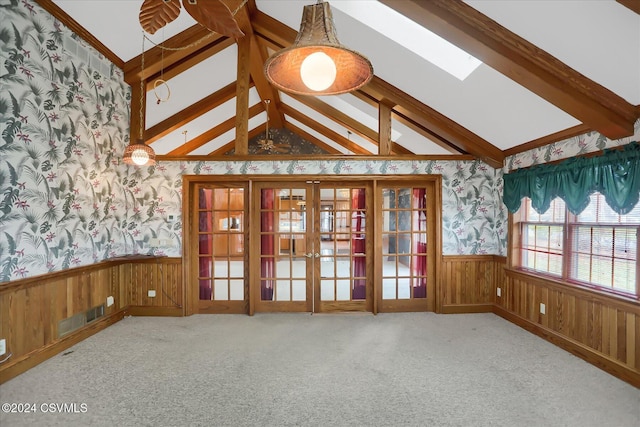 carpeted spare room with vaulted ceiling with beams, wood walls, and french doors