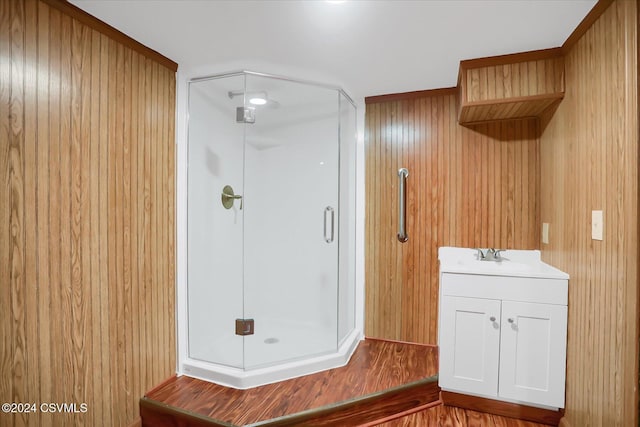 bathroom with wood walls, vanity, a shower with shower door, and wood-type flooring