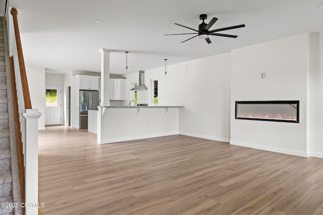 151 Hillside Ave, Elysburg, PA 17824 - unfurnished living room featuring light wood finished floors, a glass covered fireplace, a ceiling fan, a sink, and baseboards