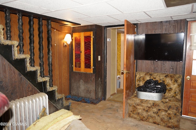 living room with radiator heating unit, concrete floors, and wooden walls