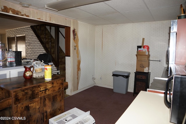 basement with dark colored carpet and a drop ceiling