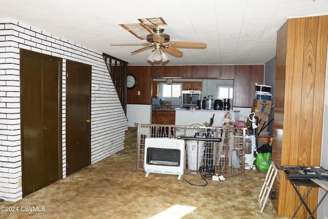 kitchen with carpet flooring, heating unit, ceiling fan, and wood walls