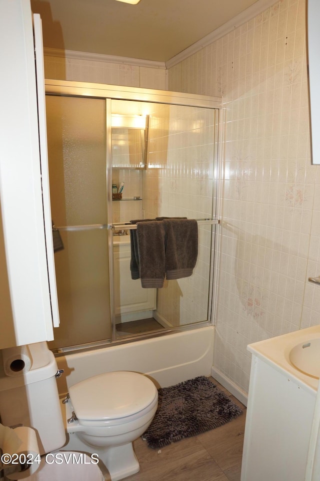 full bathroom featuring vanity, crown molding, shower / bath combination with glass door, hardwood / wood-style flooring, and toilet