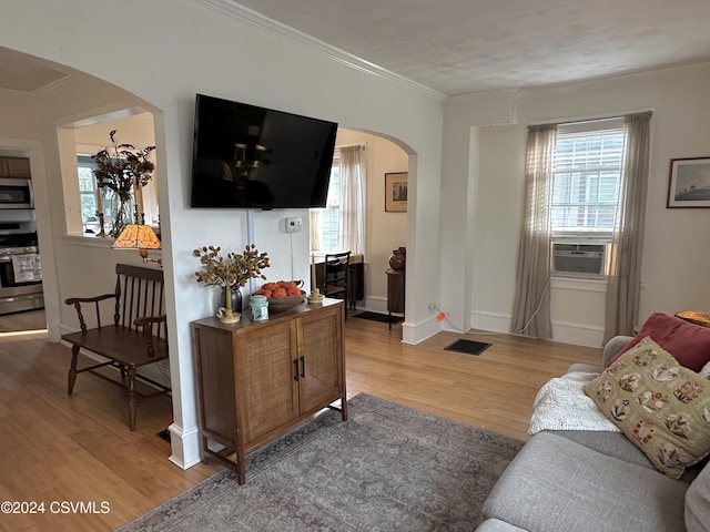 living room with cooling unit, wood-type flooring, and ornamental molding