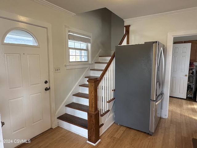 entryway with wood-type flooring, ornamental molding, and a healthy amount of sunlight