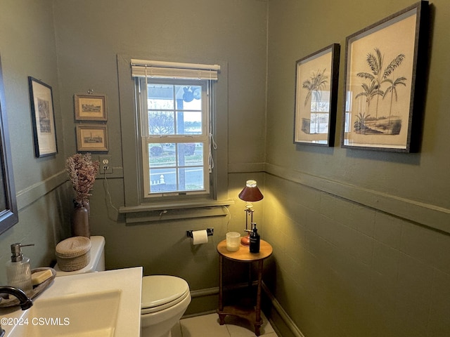 bathroom featuring tile patterned floors, toilet, sink, and tile walls