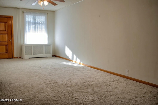 empty room with carpet flooring, ceiling fan, radiator heating unit, and crown molding