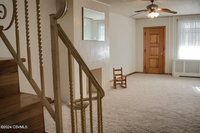 stairs with carpet, ceiling fan, and radiator heating unit