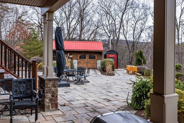 view of patio with a mountain view, outdoor dining space, a storage unit, and an outdoor structure