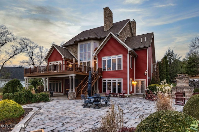 back of property with a patio, french doors, a deck, and a chimney
