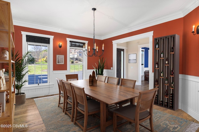 dining room featuring a notable chandelier, ornamental molding, and a wainscoted wall
