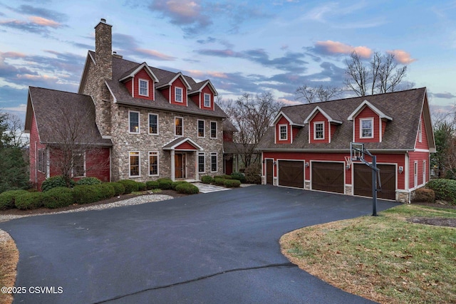 view of front of house with a chimney, stone siding, roof with shingles, and aphalt driveway