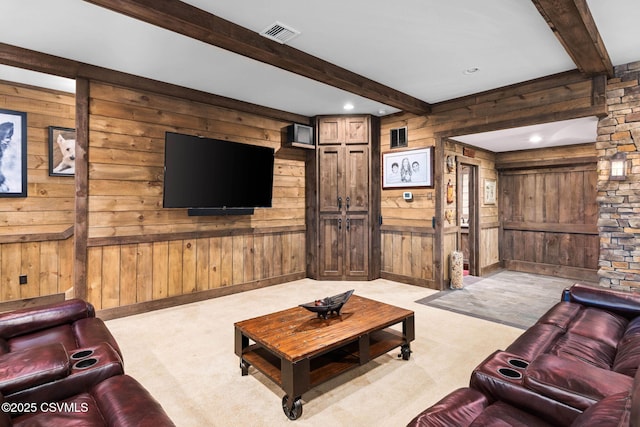 living room with light colored carpet, visible vents, wood walls, and beam ceiling