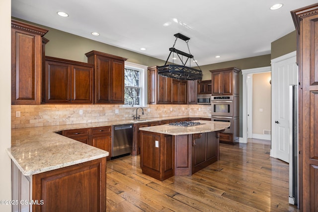 kitchen with stainless steel appliances, dark wood-style floors, a sink, and light stone counters