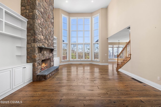 unfurnished living room featuring a fireplace, visible vents, dark wood-style flooring, and baseboards