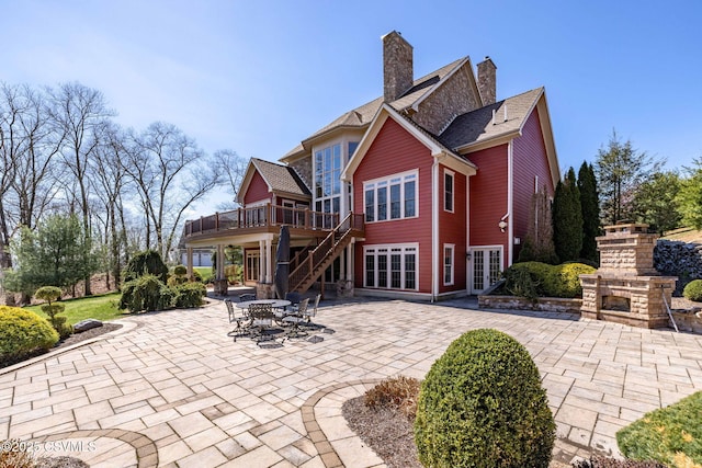 rear view of house featuring a fireplace, a chimney, a patio area, french doors, and a deck