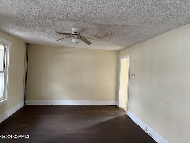 empty room with ceiling fan, dark hardwood / wood-style flooring, and a textured ceiling