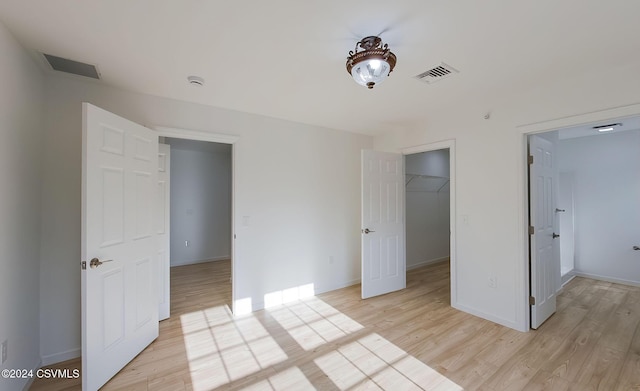 unfurnished bedroom featuring light hardwood / wood-style floors, a spacious closet, and a closet